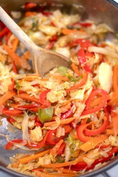 vegetables being cooked in a pan with a wooden spoon