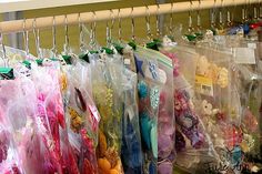 there are many items in plastic bags hanging on the rack, including hair clips and necklaces