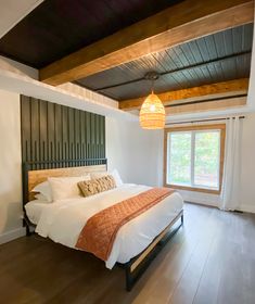 a bed sitting in a bedroom on top of a hard wood floor next to a window