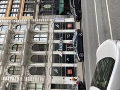 a car parked on the side of a street next to tall buildings with windows and balconies