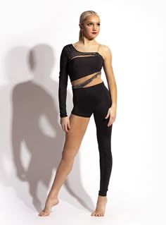 a woman standing in front of a white wall wearing a black leotard and leggings