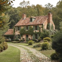 an old brick house with ivy growing on it's roof and stone pathway leading to the front door