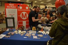 a group of people standing around a table with items on it and balloons in the background