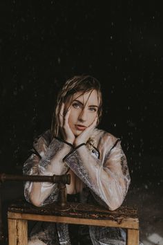 a woman sitting on top of a wooden bench in the snow with her hands to her face