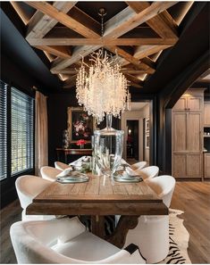 a dining room table with white chairs and a chandelier hanging from the ceiling