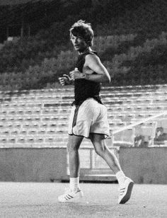 a man running on a tennis court in front of an empty bleacherside