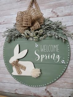 a welcome spring sign hanging on the side of a wooden wall with an easter bunny