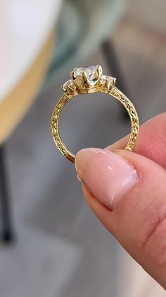 a hand holding a gold ring with two diamonds