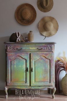 three hats are hanging on the wall above an old dresser with two doors and one door open