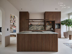 a kitchen with marble counter tops and wooden cabinets in the center, along with a potted plant