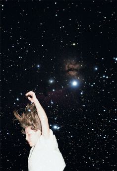 a young man in white shirt flying through the air with his arms up and stars in the background