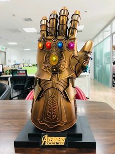 an iron man hand statue on top of a wooden table in front of a glass wall