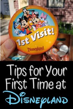 a person holding up a disneyland pin with the title tips for your first time at disneyland