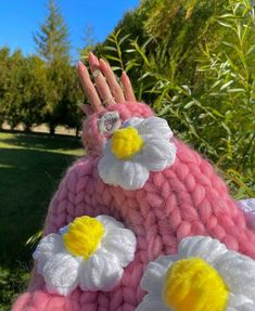 a close up of a knitted doll with flowers on it's head and hands