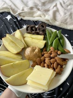 a white plate topped with sliced apples, almonds and green beans next to cheese