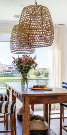 a dining room table with flowers in a vase on it and chairs around the table