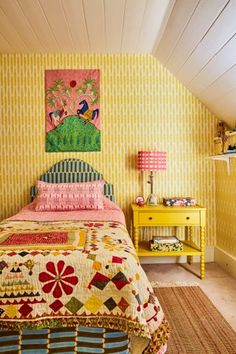 a bedroom with yellow walls and colorful bedding