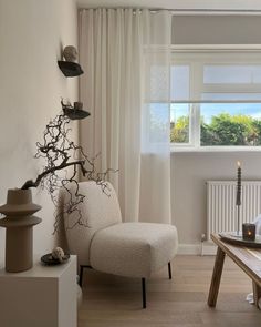 a living room filled with furniture next to a window covered in white curtains and drapes