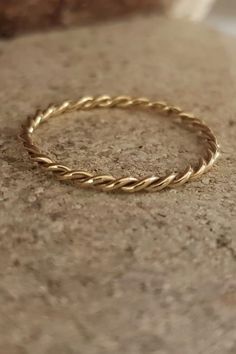 a gold rope ring sitting on top of a stone slab with the end of it