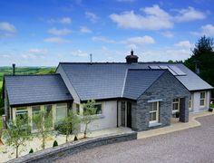 a house with a large driveway in front of it and lots of greenery on the other side