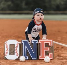 a baby is playing with the letters one and baseballs