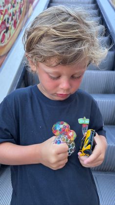 a young boy is playing with his toy at the bottom of an escalator