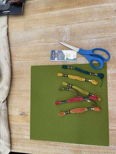 some scissors are laying on top of a piece of green paper next to other items