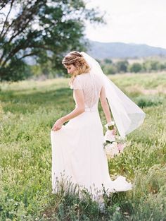 a woman in a wedding dress standing in the grass