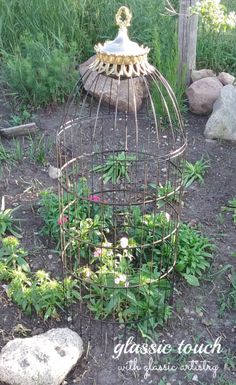 a bird cage sitting in the middle of a garden