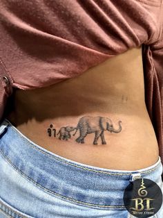 an elephant tattoo on the side of a woman's stomach, with three smaller elephants behind it