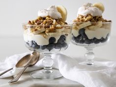 two glasses filled with dessert sitting on top of a table