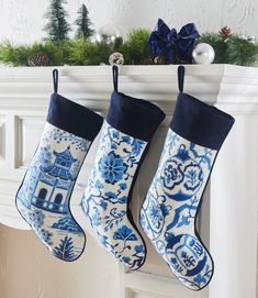 two blue and white christmas stockings hanging from a mantel