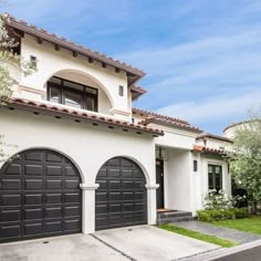 a white house with two black garage doors