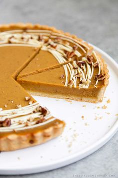 a slice of pumpkin pie on a plate with the rest of the pie in front