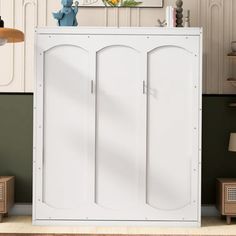 a white cabinet with two doors in a room next to a lamp and pictures on the wall