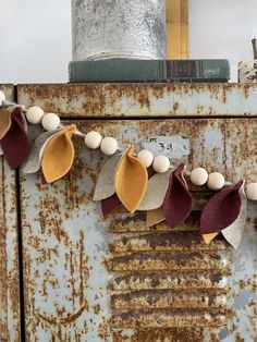 an old rusty refrigerator with some felt leaves and eggs hanging from it's handles