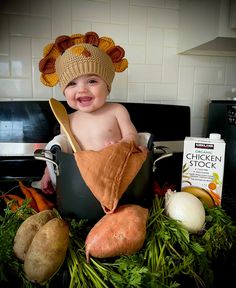 a baby wearing a turkey hat sitting in a pot filled with vegetables and other foods