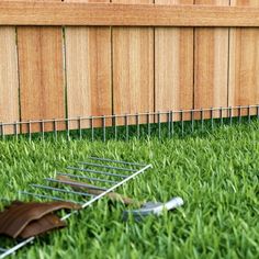 a lawn mower laying in the grass next to a fence and wooden slats