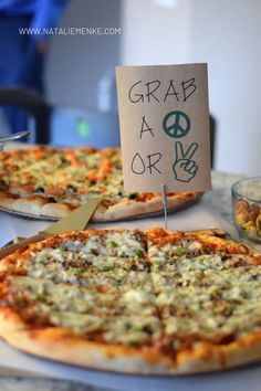 two pizzas sitting on top of a table with a sign that says grab a slice