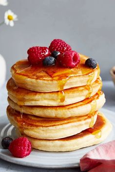 a stack of pancakes topped with berries and syrup