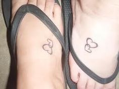 two people with tattoos on their feet and one has a heart tattoo on the foot