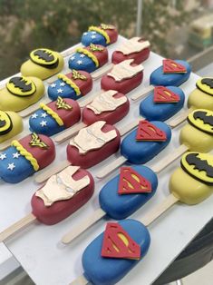 a table topped with lots of cupcakes covered in superman and batman symbol icing