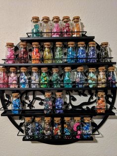 a wall mounted shelf filled with lots of different colored glass bottles on top of it