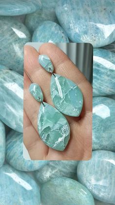 a hand holding some green rocks in front of blue and white stones, with one rock being held up to the camera