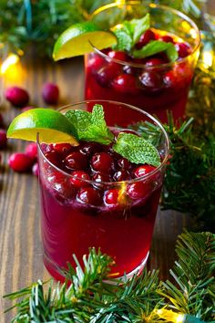 two glasses filled with cranberry shrub and lime