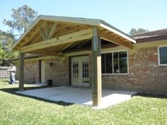 a covered patio area in front of a brick building with a person standing outside the door