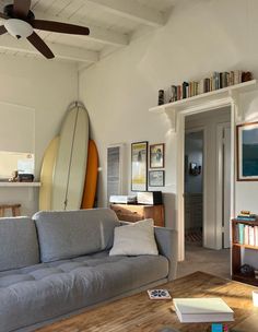 a living room filled with furniture and a surfboard on top of a shelf above the couch