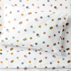 two pillows on top of each other in front of a white background with multicolored circles