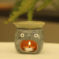 a small ceramic animal candle holder with a lit candle in it's mouth and eyes