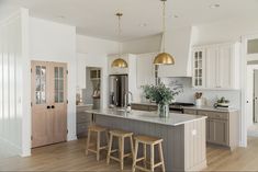 a large kitchen with an island and stools in the center, surrounded by white cabinets